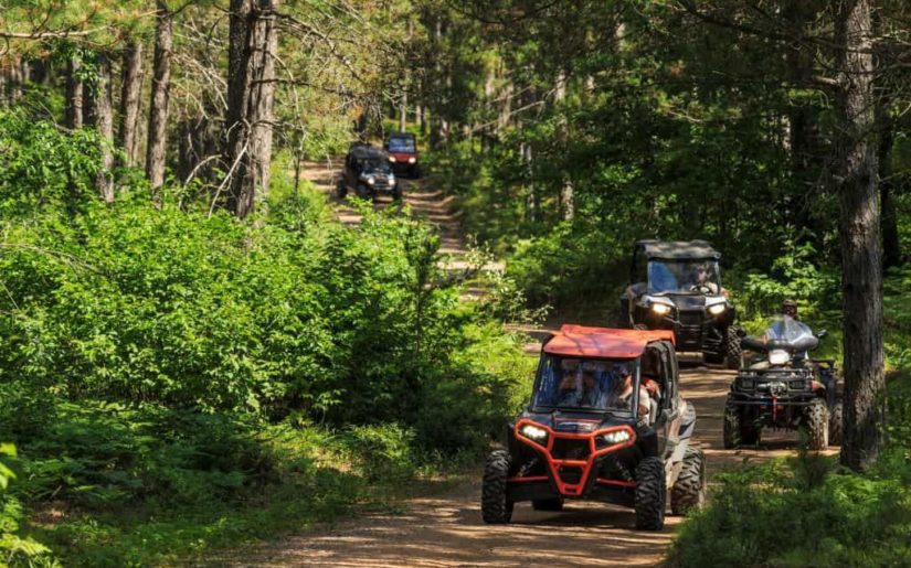 Off-road utility vehicles riding on a dirt path.